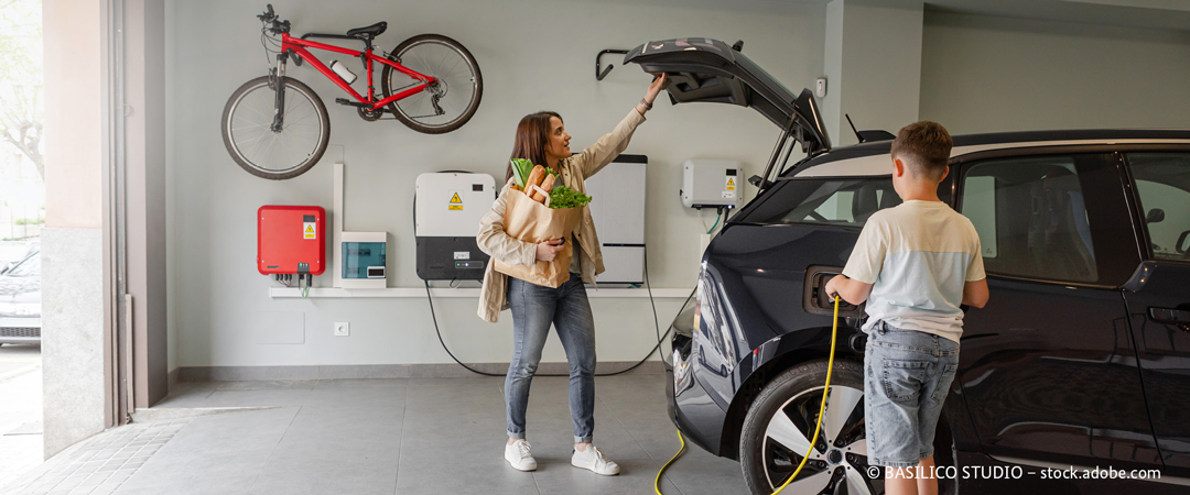 Frau und Kind in einer Garage mit E-Auto. Frau und Kind in einer Garage mit E-Auto.