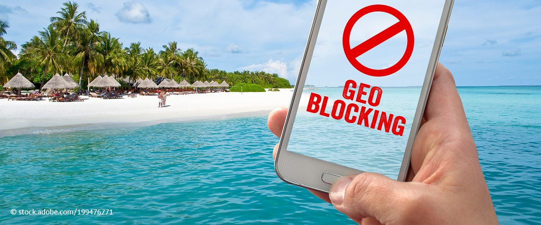 Jemand hält an einem Strand ein Smartphone in der Hand, auf dessen Display "Geoblocking" steht. Jemand hält an einem Strand ein Smartphone in der Hand, auf dessen Display "Geoblocking" steht.