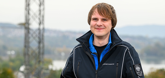 Junger Mann mit blauer Jacke vor unscharfem Hintergrund Junger Mann mit blauer Jacke vor unscharfem Hintergrund