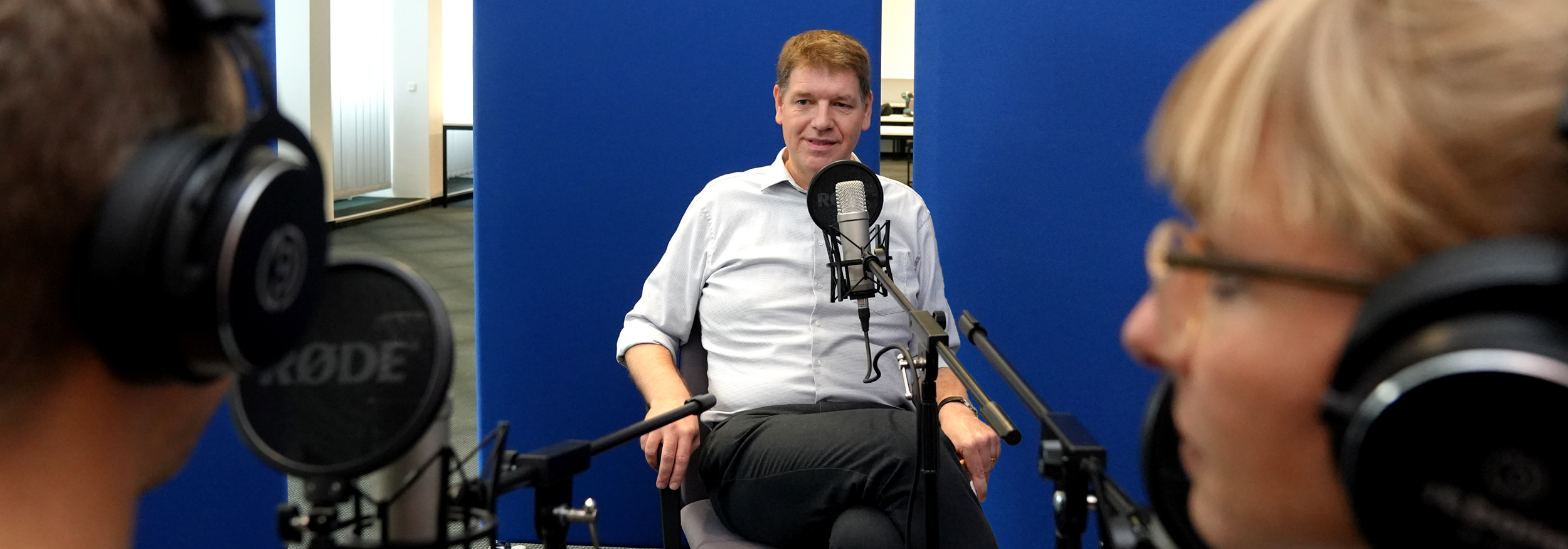 Podcast Aufnahme mit Dr. Ulrich Geers, mittig im Bild vor dem Podcast-Mikro. Die beiden Hosts rechts und links im Bild. Podcast Aufnahme mit Dr. Ulrich Geers, mittig im Bild vor dem Podcast-Mikro. Die beiden Hosts rechts und links im Bild.